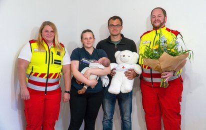 Baby Alessio mit seinen Eltern und Rettungssanitäterinnen des Roten Kreuzes.