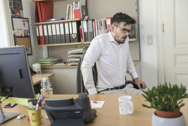 Mann hat im Büro Asthmaanfall und bekommt keine Luft.