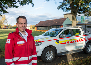 Robert Strauss - Offizier vom Dienst - steht in Rotkreuz-Einsatzuniform vor einem Kommandofahrzeug.