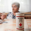 Ein Rotkreuz-Mitarbeiter reicht einer Klientin die Rokreuzdose des Roten Kreuzes Niederösterreich.