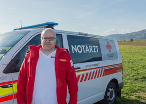 OA Dr. Markus Gschanes - Bezirksrotkreuzarzt - steht in Rotkreuz-Einsatzuniform vor einem Notarzteinsatzfahrzeug im Freien.