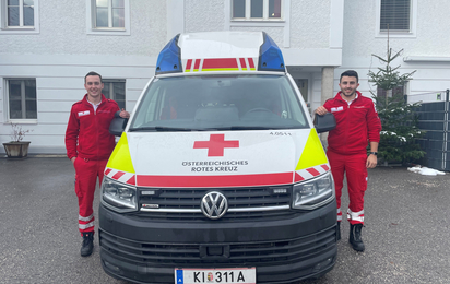 Zwei Zivildiener stehen rechts und links neben einem Rettungsauto