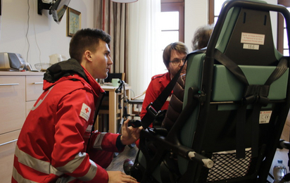 Zwei Rettungssanitäter holen eine Dame aus dem Seniorenzentrum zum Transport ins Krankenhaus ab.