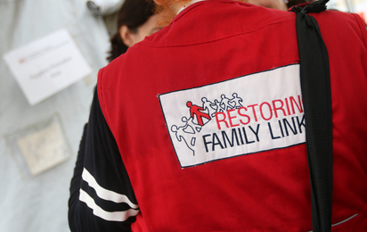 Person von hinten mit Rotkreuz Jacke und der Aufschrift Restoring Family Links