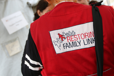 Person von hinten mit Rotkreuz Jacke und der Aufschrift Restoring Family Links