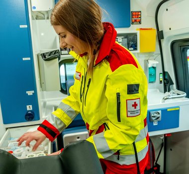 Eine Sanitäterin beim Fahrzeugcheck in der neuen gelbroten Uniform.