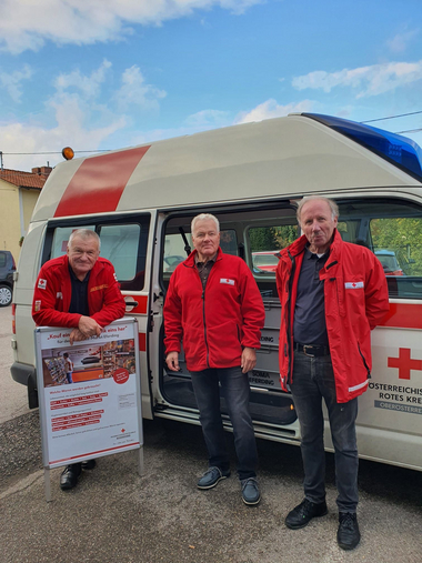 3 freiwillige Rotkreuz-Markt-Fahrer vor dem Transportfahrzeug