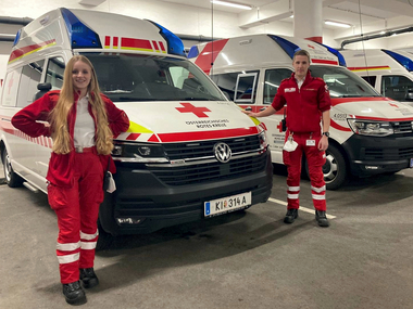 Zwei Rettungssanitäter stehen vor den Rettungsautos in der Garage