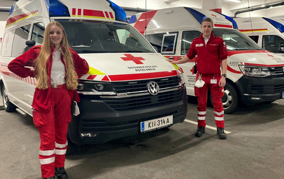 Zwei Rettungssanitäter stehen vor den Rettungsautos in der Garage