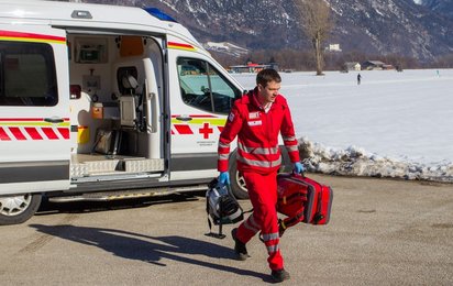 Ein Rotkreuz Sanitäter kommt am Unfallort an. In seiner Hand befindet sich ein Notfallrucksack