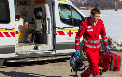 Ein Rotkreuz Sanitäter kommt am Unfallort an. In seiner Hand befindet sich ein Notfallrucksack