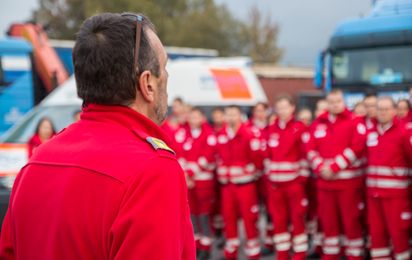 Bezirksrettungskommandant vor einer Gruppe Sanitäter neben einem Rettungstransportwagen