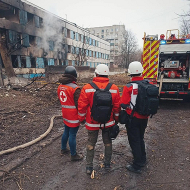 Rotkreuz-Mitarbeiterinnen stehen vor zerstörtem Haus