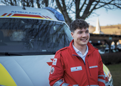 Ein freiwilliger Mitarbeiter aus dem Rettungsdienst vor einen Rettungswagen.