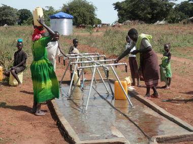 Menschen bedienen eine Wasserpumpe in Uganda