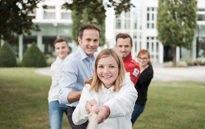 Fünf Menschen ziehen gemeinsam an einem Seil.