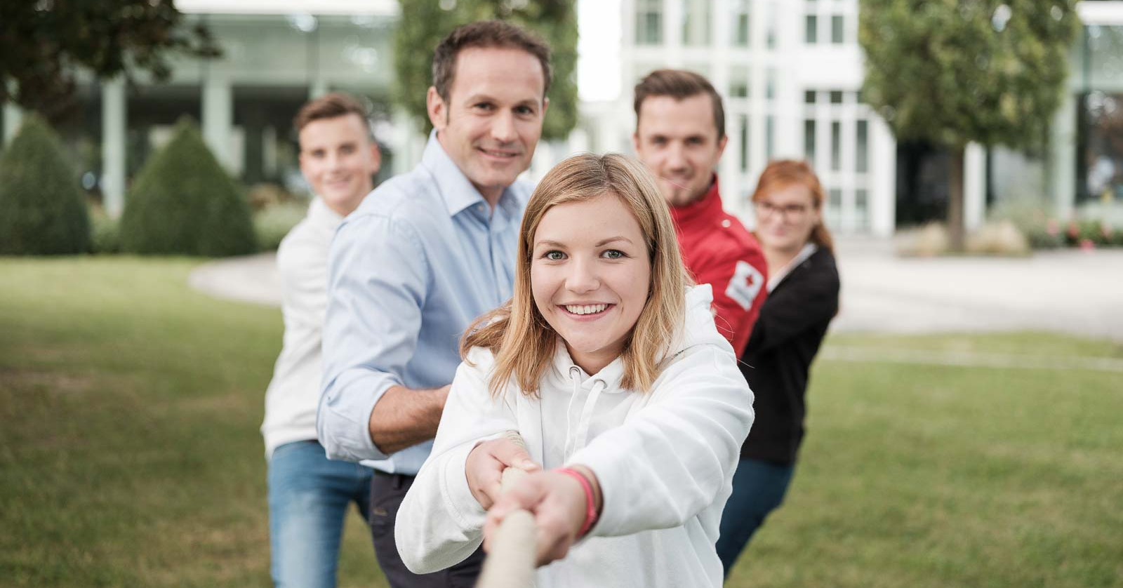 Fünf Menschen ziehen gemeinsam an einem Seil.