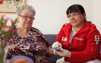 Eine Rotkreuz-Mitarbeiterin misst im Rahmen der Hauskrankenpflege bei einer Klientin den Blutzucker.