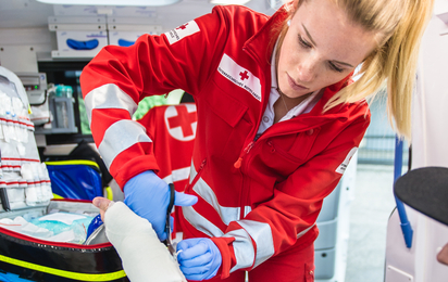 Sanitäterin verbindet Unterarm eines Patienten