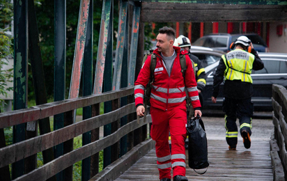 Rotkreuz-Mitarbeiter in Uniform geht über eine Brücke.