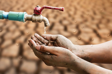 eine Person hält ihre Hände unter einem Wasserhahn aus dem Wasser tropft