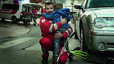 Ein Rotkreuz-Mitarbeiter aus dem Rettungsdienst hält ein Kind im Arm