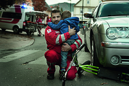 Ein Rotkreuz-Mitarbeiter aus dem Rettungsdienst hält ein Kind im Arm