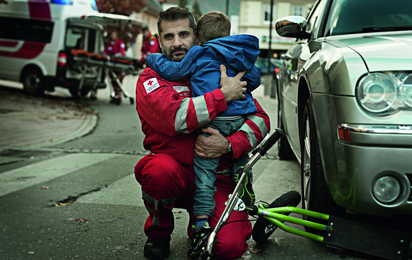 Ein Rotkreuz-Mitarbeiter aus dem Rettungsdienst hält ein Kind im Arm