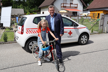 Cornelius Obonya mit Kind-Darstellerin vor Wagen des Mobilen Hospizes