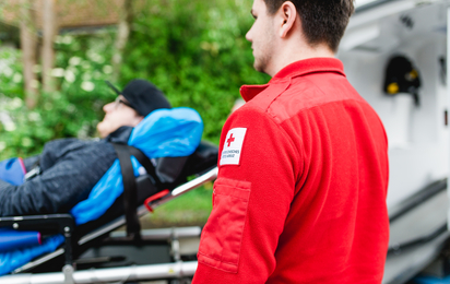 Sanitäter im Vordergrund, Patient auf Trage im Hintergrund