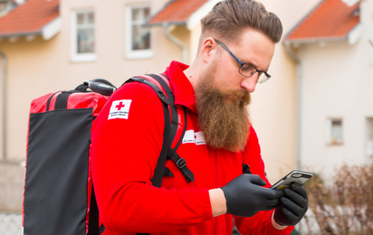 Ein First Responder ist unterwegs zum Notfall. Am Rücken trägt er einen Notfallrucksack, in der Hand hält er ein Handy, mit dem er alarmiert wurde.