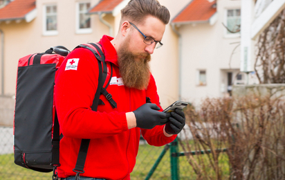 Ein First Responder ist unterwegs zum Notfall. Am Rücken trägt er einen Notfallrucksack, in der Hand hält er ein Handy, mit dem er alarmiert wurde.