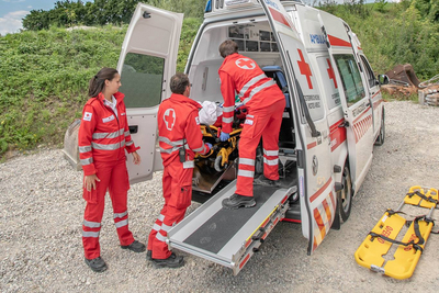 Drei Sanitäter sind am Notfallort eingetroffen und haben die verletzte Person in den Rettungswagen gebracht.