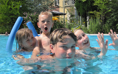 Vier Kinder baden in einem Pool.