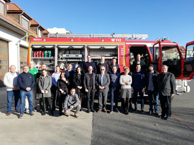 Eine Gruppe steht vor einem Feuerwehrauto.