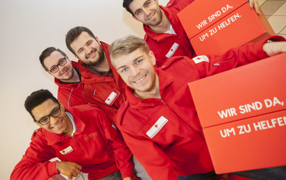 Fünf junge Männer in Rotkreuz-Uniform halten einen Würfel aus Karton mit der Aufschrift "Wir sind da, um zu helfen". Das ist der Leitsatz des Roten Kreuzes