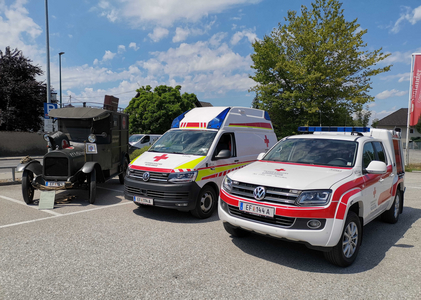 historischer Sanitätswagen, modernes Rettungsauto und modernes Notarztdienst-Fahrzeug stehen nebeneinander