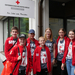 Jugendgruppenleiterin Tanja steht mit ihrer Jugendgruppe vor dem Gebäude des Jugendrotkreuzes in Linz.