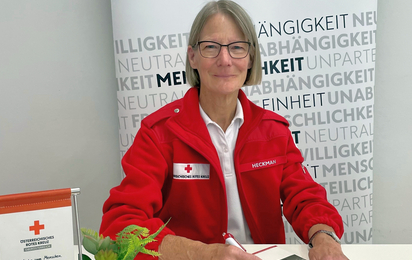 Gesundheits- und Sozialbegleiterin Bernardine Heckman sitzt am Tisch mit einem Kugelschreiber in der Hand