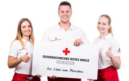 Zwei Sanitäterinnen und ein Sanitäter präsentieren ein Plakat mit dem Logo vom ÖRK Hall in Tirol.