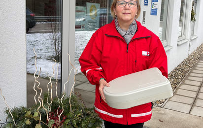 Helga Stadt mit Essen auf Rädern-Box vor der Dienststelle