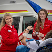 Zwei weibliche Sanitäterinnen vor einem Rettungsauto wie sie einen Patienten betreuen.