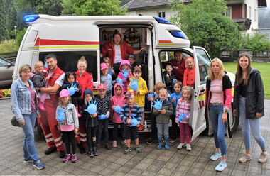 Gruppenfoto Rettungswagen, Sanitäter:innen und die Kinder des Kindergarten Kirchbach im Bezirk Hermagor.