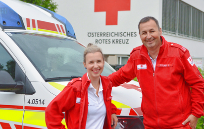 Zwei Rettungssanitäter stehen vor einem Rettungsauto