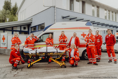 Mitarbeiter:innen der Ortsstelle Königswiesen vor dem Rettungsauto und der Dienststelle