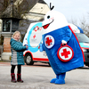 ROKO mit dem roten Herz, das Maskottchen vom JRK, steht mit einem blonden Mädchen vor dem Roko-Mobil.