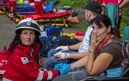 Sanitäterin betreut eine Patienten auf einem Tragstuhl