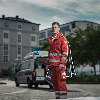 Zivildiener vom OÖ. Roten Kreuz vor einem Rettungsauto mit offener Heckklappe..