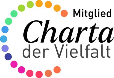 zu sehen ist das bunte Logo vom Charta der Vielfalt, ein Schriftzug in einem gepunktelten Halbkreis