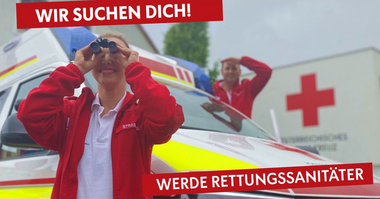 Rettungssanitäterin steht vor einem Rettungsauto und schaut durch ein Fernglas